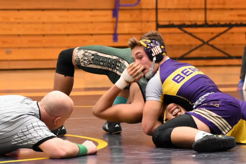 A group of men wrestling on the ground.