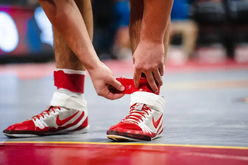 A person tying their shoe laces on the floor