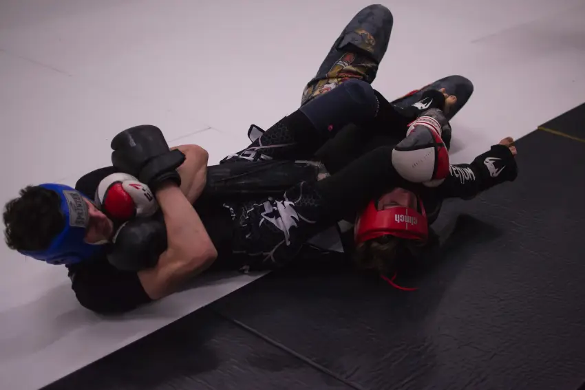 Two people are laying on the ground with boxing gloves.